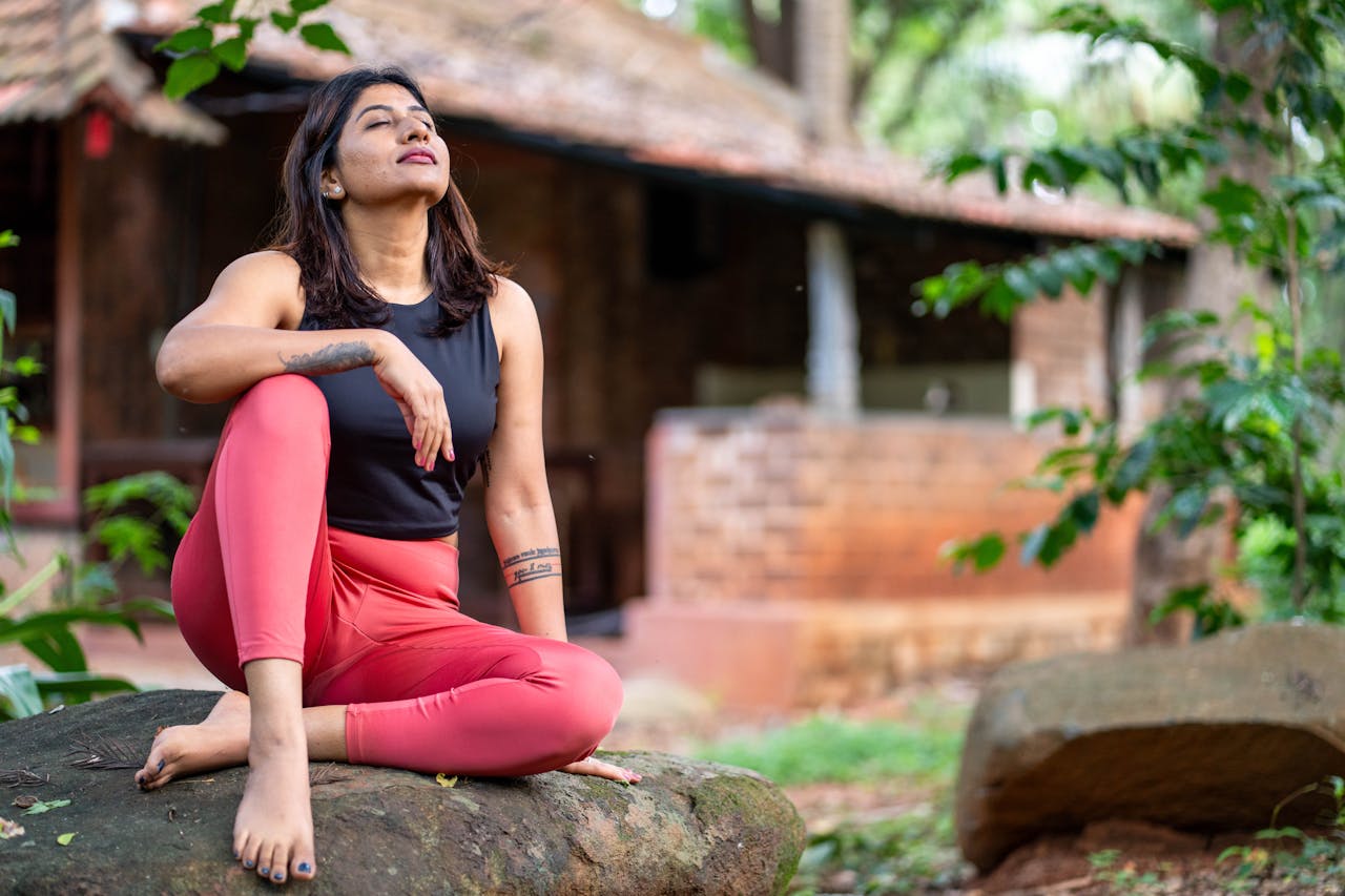 Adult woman practicing meditation on a rock, blending with nature's tranquility.