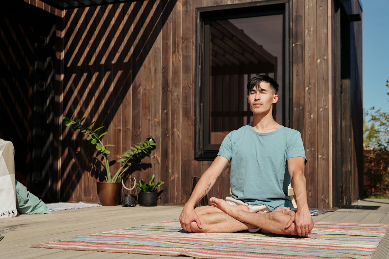 Man meditating outdoors with closed eyes, enjoying a peaceful moment on a sunny day.