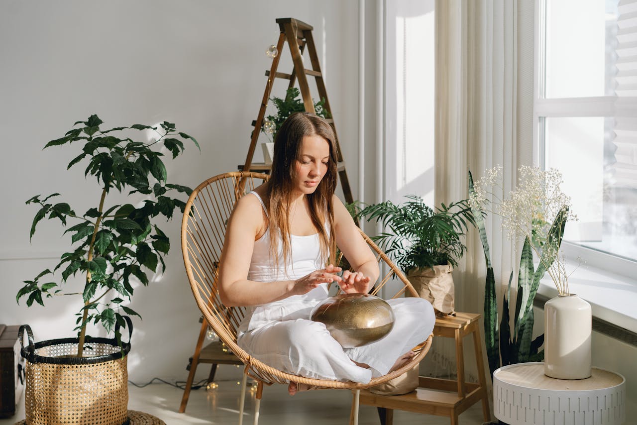 A woman meditates indoors surrounded by houseplants, creating a calming atmosphere.